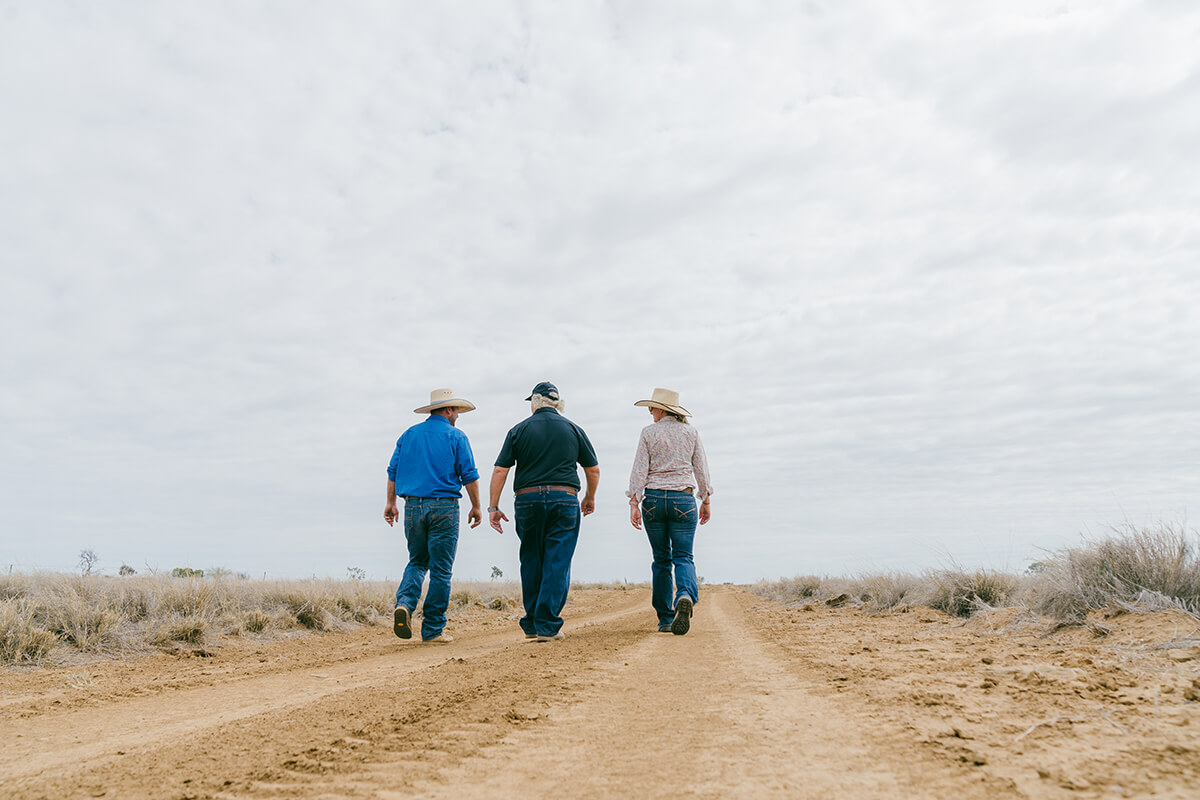 Three people walking down rural dirt road