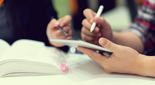 Two people's hands with one using an ipad
