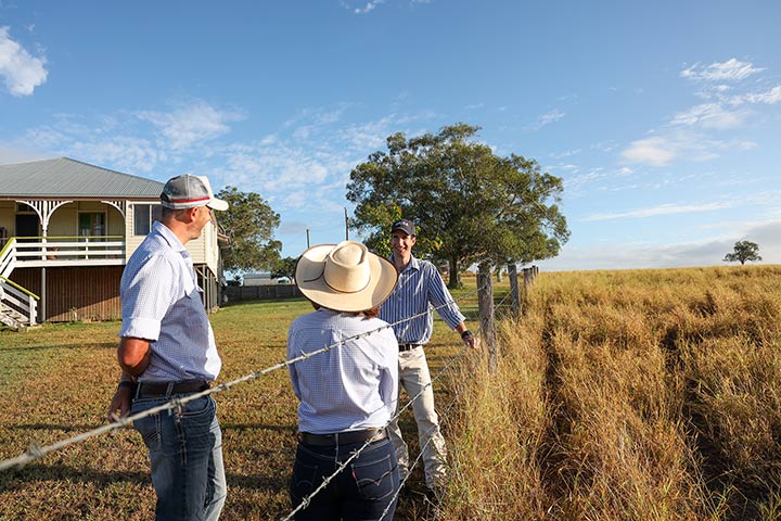Dan Elder standing at fence talking to primary producers