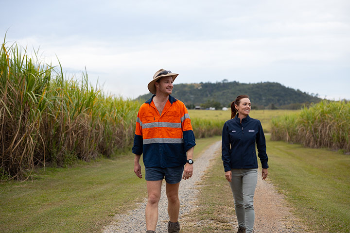 Dylan Wedel walks along a dirt road with Regional Area Manager Tegan McBride as they inspect the Wedel's cane crop.