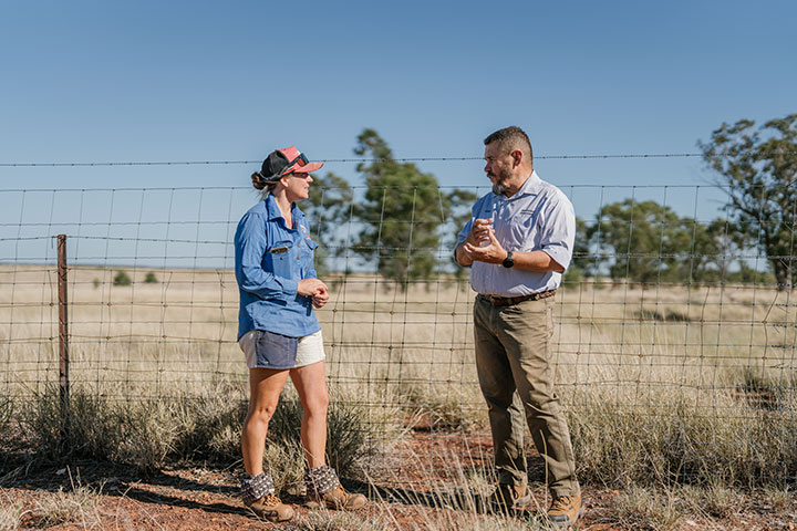 Sarah Packer is standing with Regional Area Manager for the Maranoa and South West, Terry Pulsford in a paddock next to an exclusion fence