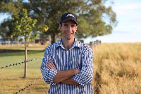 A man stands smiling at the camera with his arms folded against his chest 